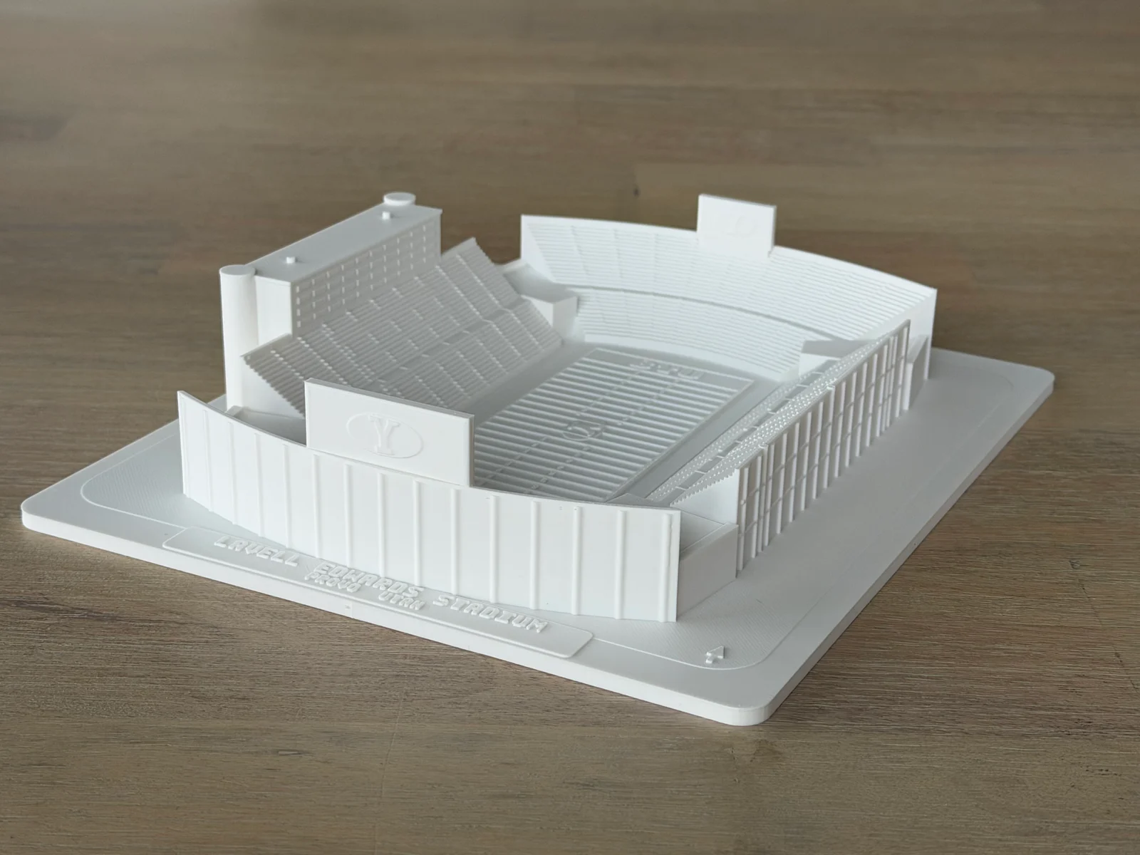 The white 3D-printed model of LaVell Edwards Stadium on a wood surface.